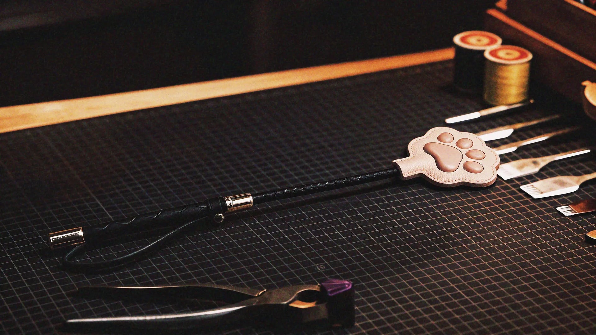 Above Zero Studio craft scene with cat paw paddle, leather tools, and workbench materials
