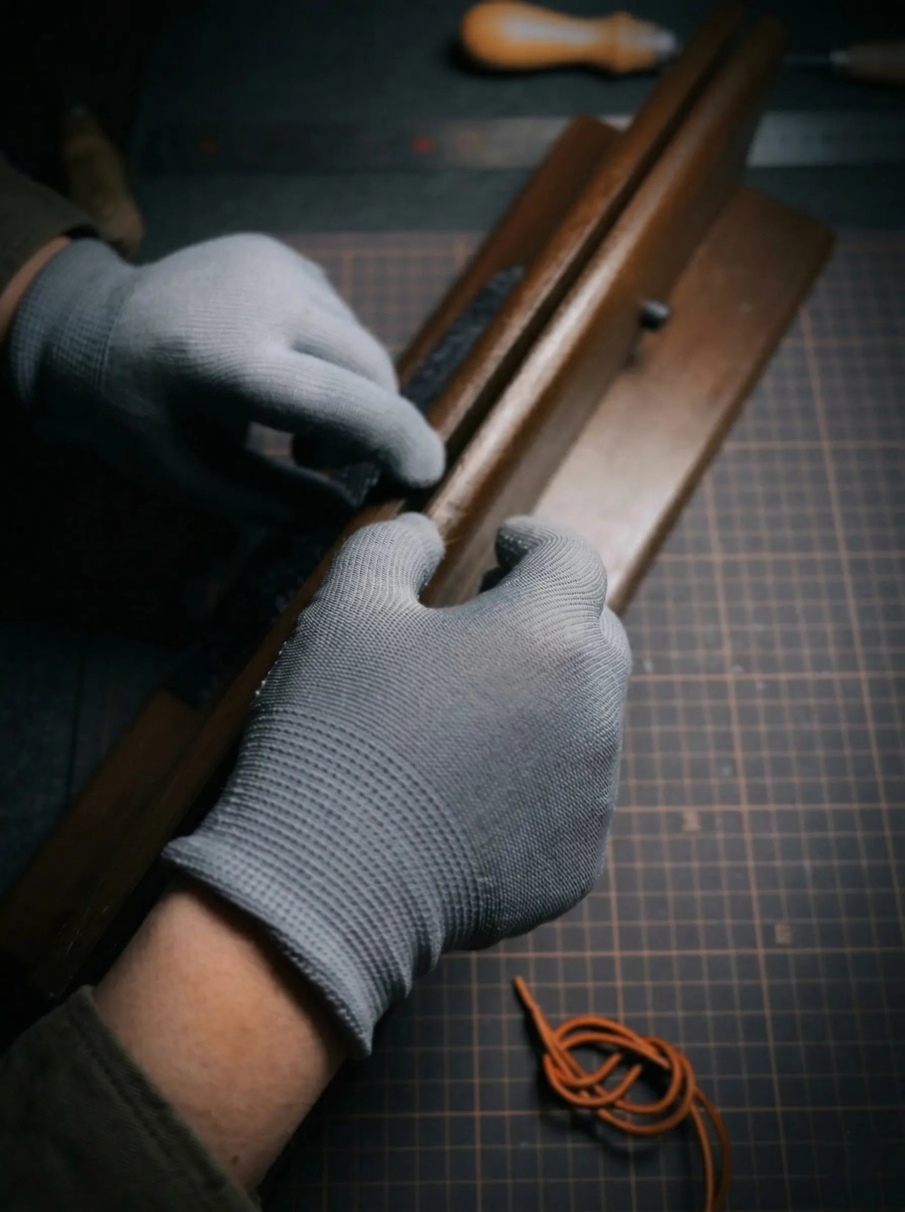 Above Zero Studio atelier workbench scene with gloved hands crafting leather on a cutting mat