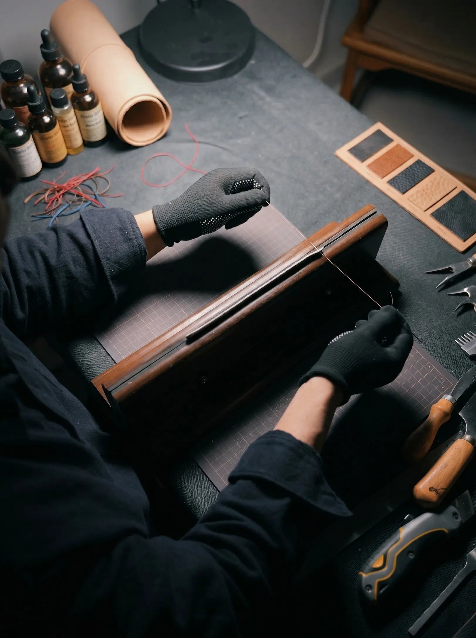 Above Zero Studio handmade leather workshop scene with gloved hands working on blush leather