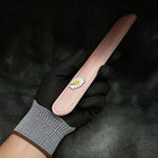 Daisy Hush Slim Leather Spanking Paddle angled on black satin, showing blush pink leather and daisy accent.