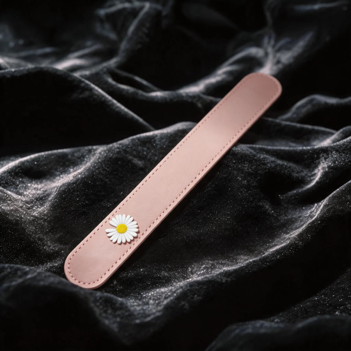 Daisy Hush Slim Leather Spanking Paddle blush pink leather slim paddle on black satin with daisy accent.
