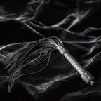 Midnight Discipline Leather Flogger matte black leather flogger on black satin with slim tails.