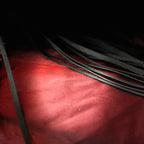 Midnight Discipline Leather Flogger red satin close-up showing matte black leather tails and wrapped handle.