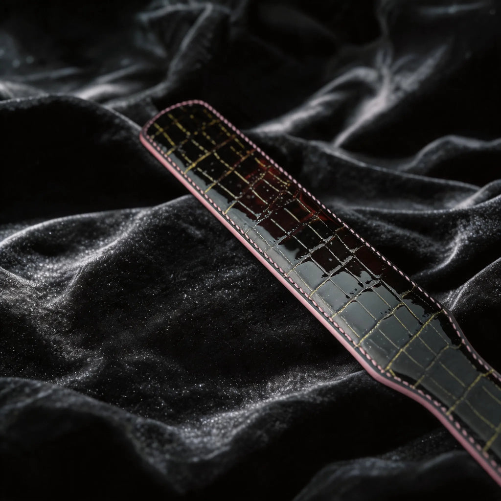 Noir Grid Patent Texture Leather Paddle hand-held studio detail showing grid texture and glossy edge.