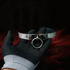 Python Lock O-Ring Leather Collar angled on black satin, showing white and black python-textured leather and O-ring front.