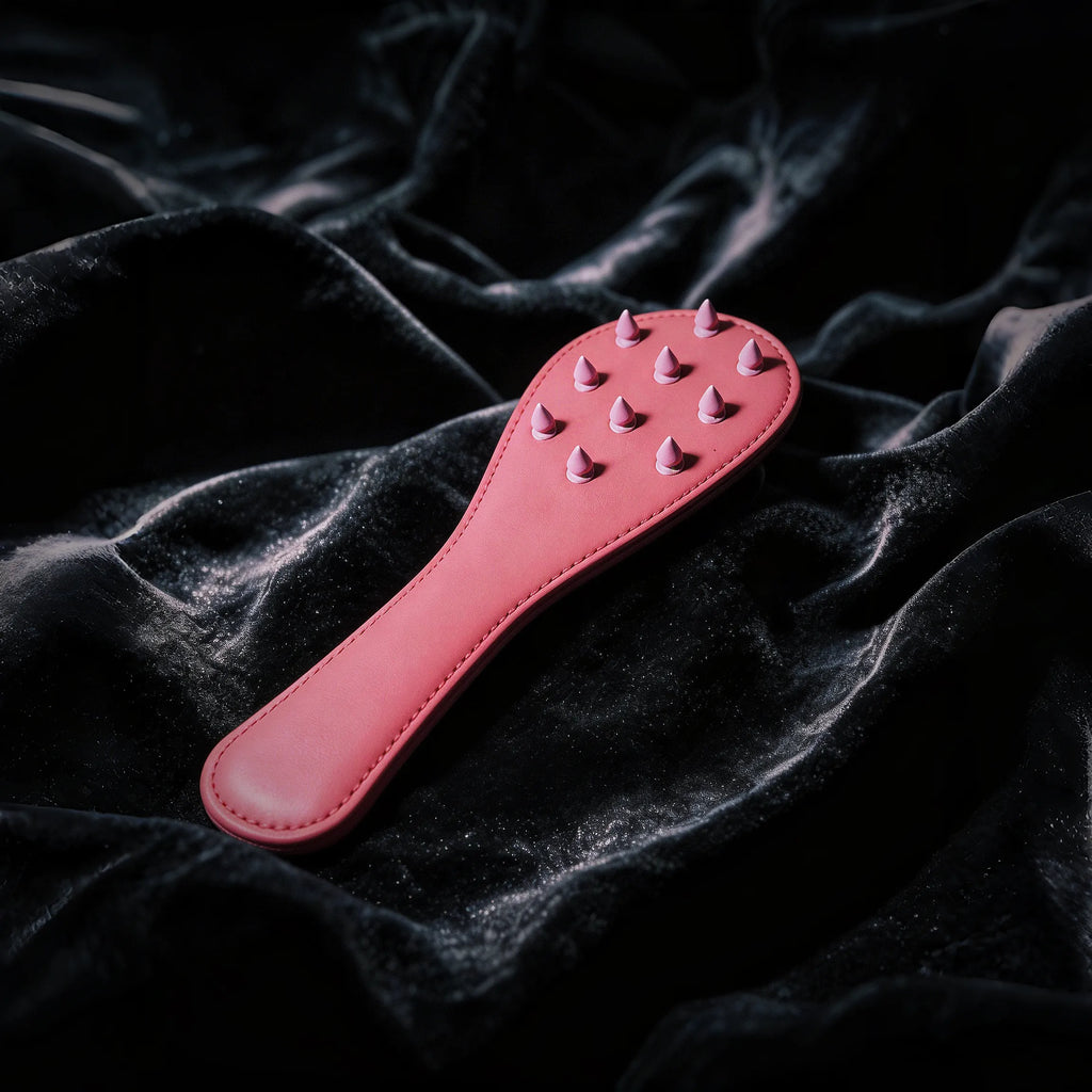 Rose Thorn studded leather paddle front view with blush leather surface and sculptural raised details