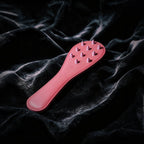 Rose Thorn studded leather paddle front view with blush leather surface and sculptural raised details