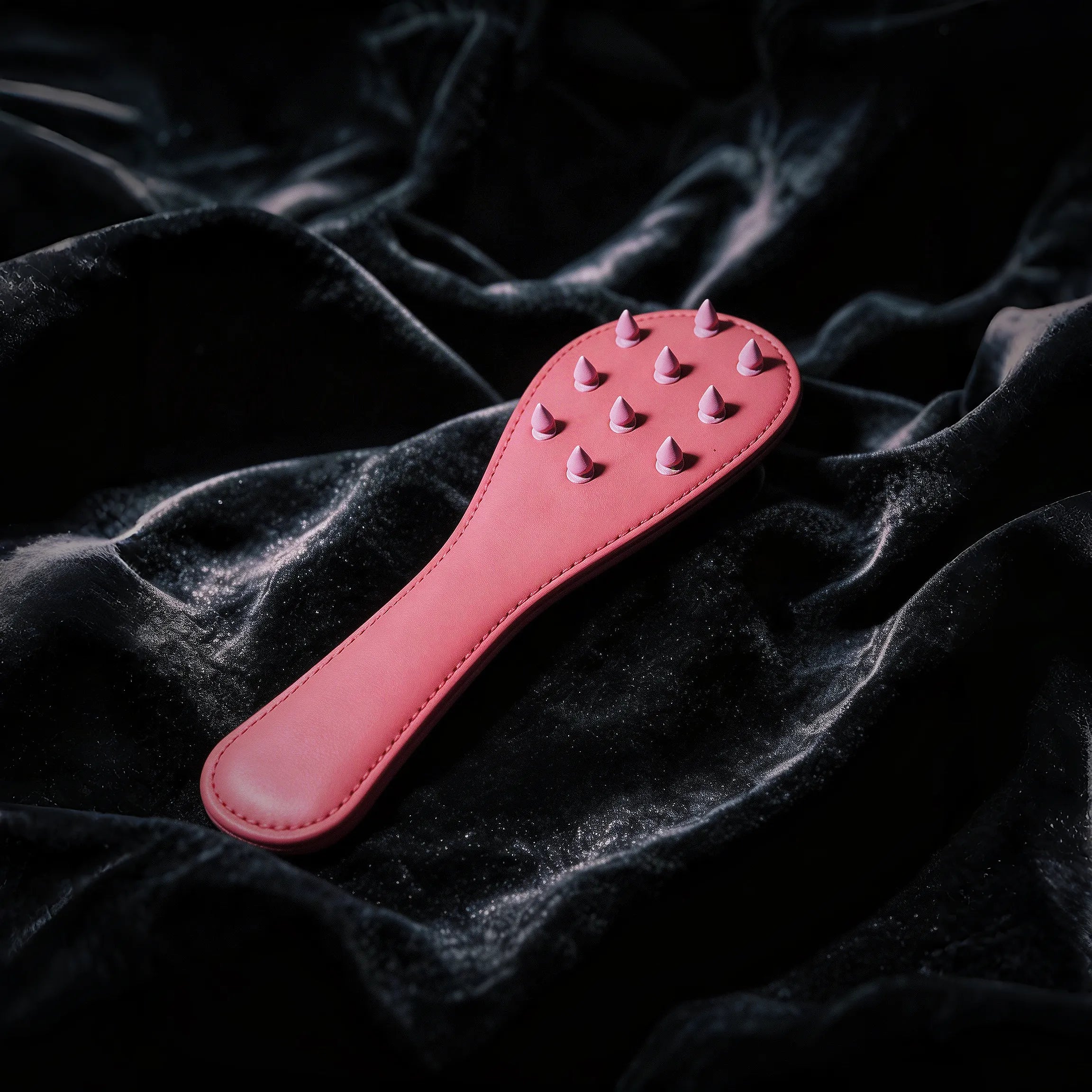 Rose Thorn studded leather paddle front view with blush leather surface and sculptural raised details
