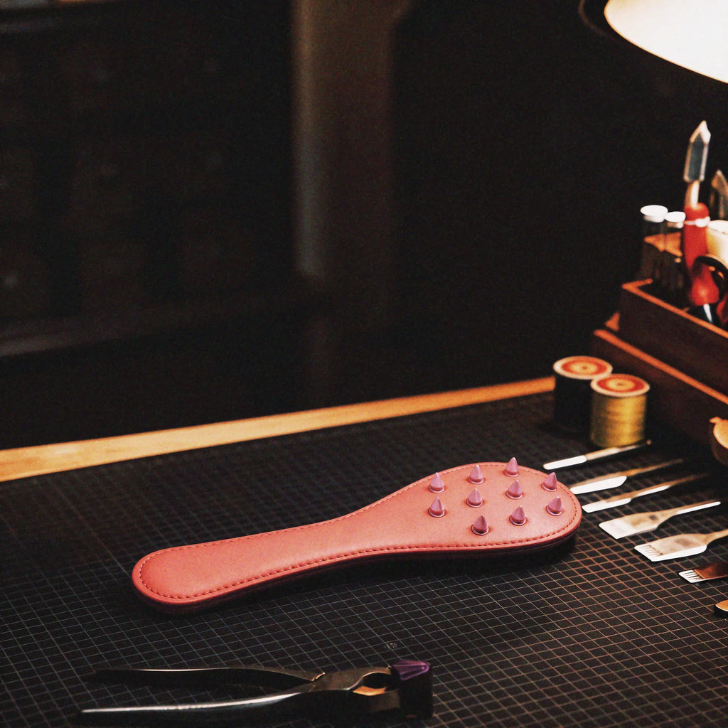 Rose Thorn studded leather paddle studio display featuring blush leather body and stable grip