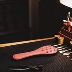 Rose Thorn studded leather paddle studio display featuring blush leather body and stable grip