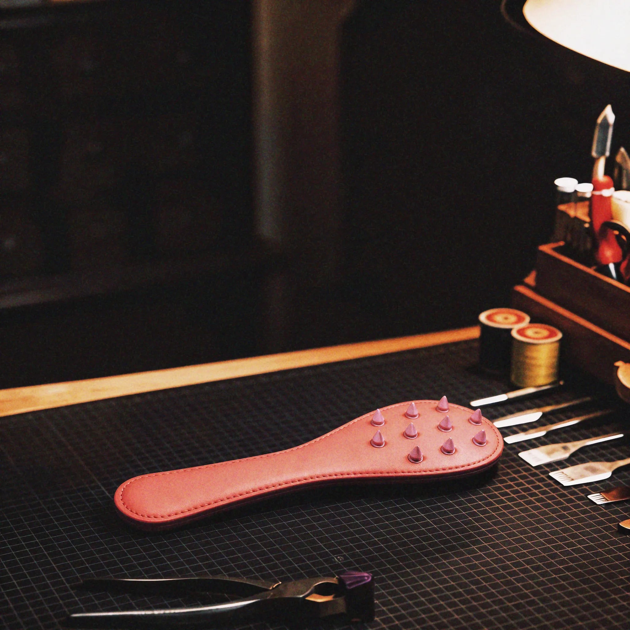 Rose Thorn studded leather paddle studio display featuring blush leather body and stable grip