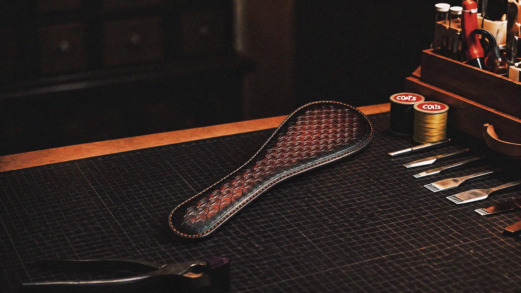 Scarlet Scale Textured Leather Paddle warm tabletop studio scene with wooden box, crimson and black leather, and scale texture.