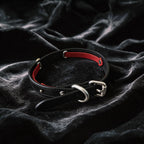 Serpent Mark Pendant Leather Collar angled on black satin, showing black and crimson leather and serpent pendant.
