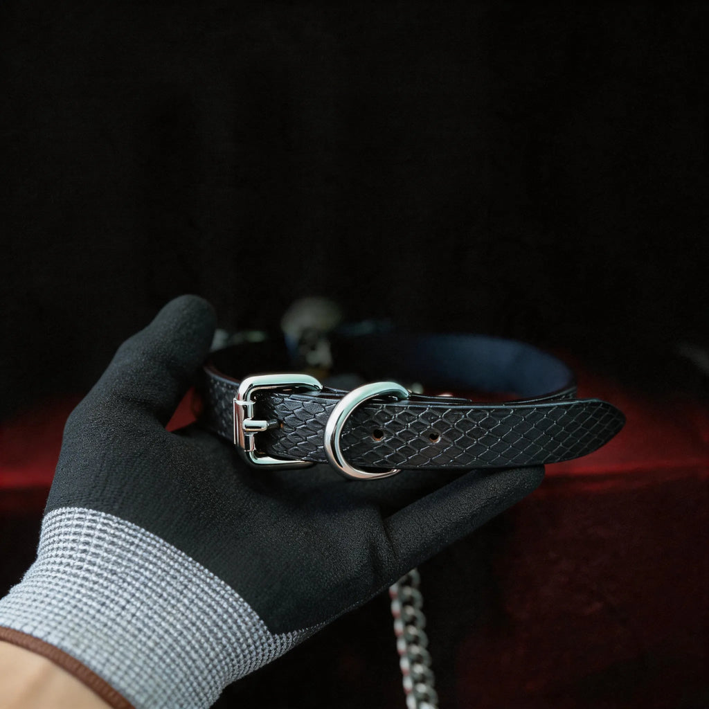 Serpentine Grace Bow Bell Leather Collar hand-held red satin scene with black and white leather and silver chain hardware.