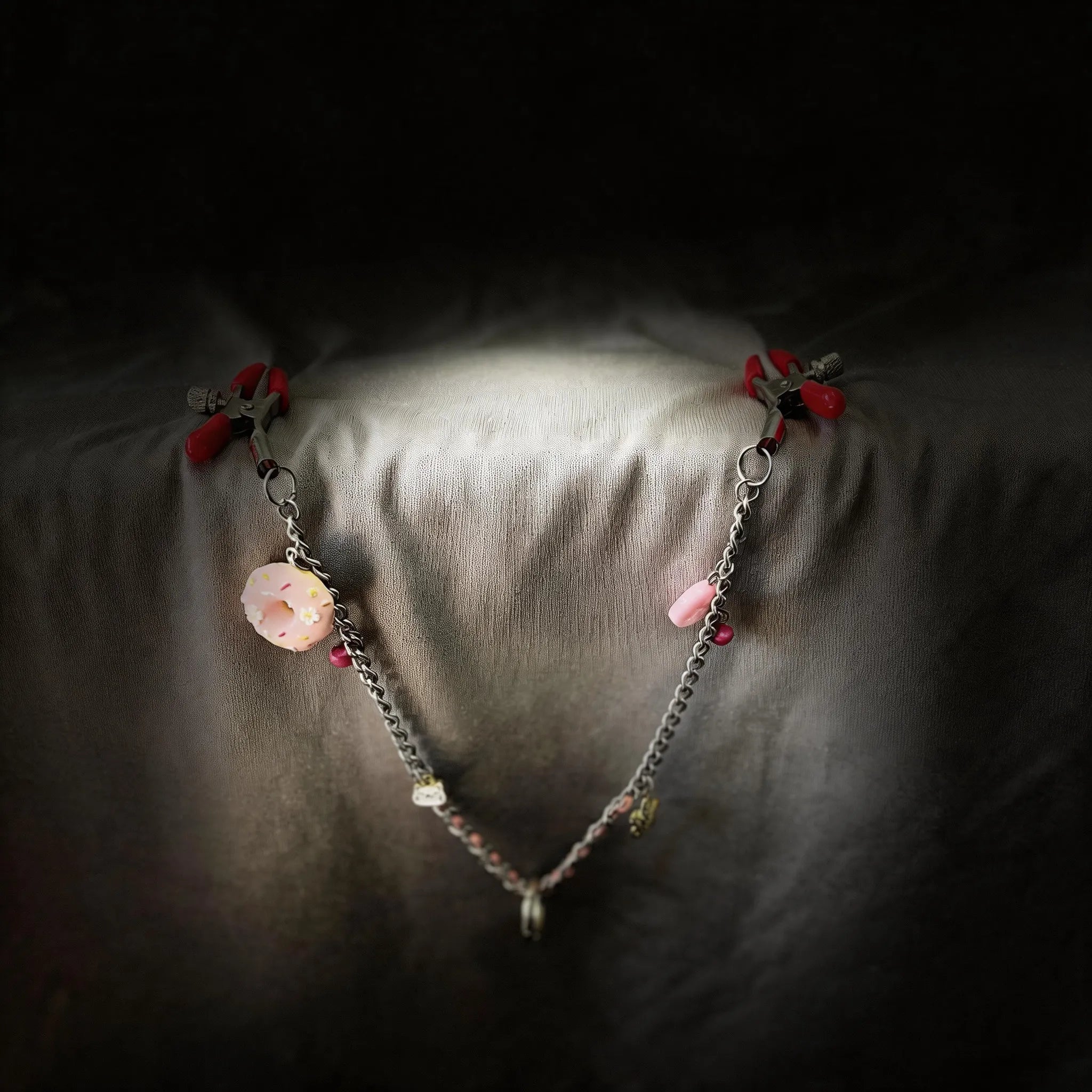 Sugar Tease Candy Charm Metal Nipple Clamps silver and red metal nipple clamps on black satin with candy charm.