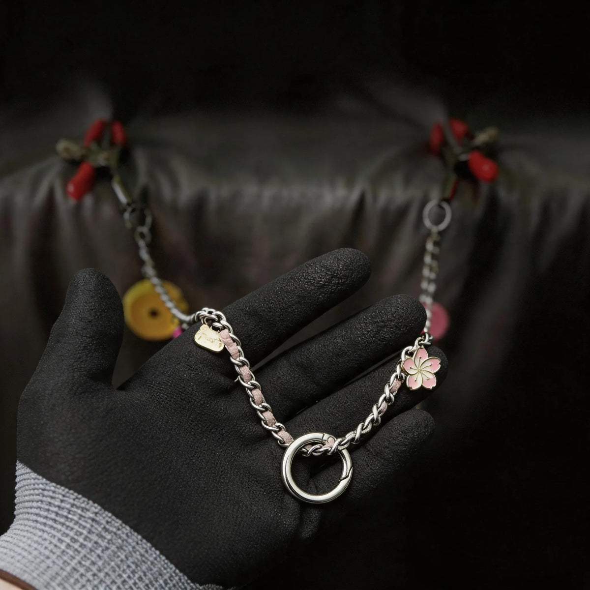 Sugar Tease Candy Charm Metal Nipple Clamps hand-held detail showing silver and red metal, candy charm, and chain.