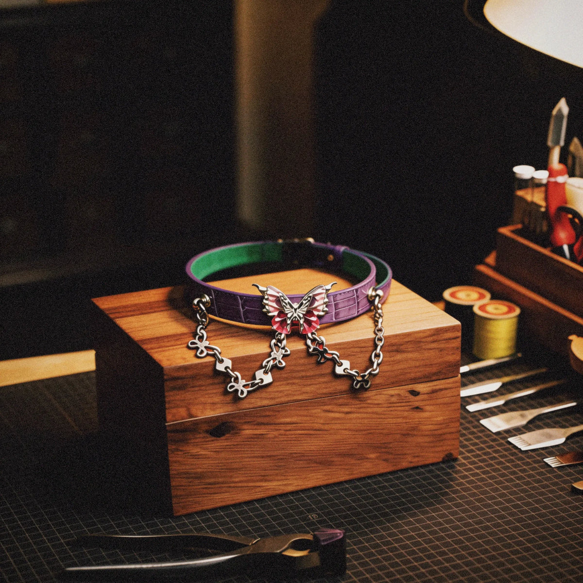 Violet Flutter butterfly chain leather collar studio display on a wooden stand with embossed lavender leather, mint inner accent